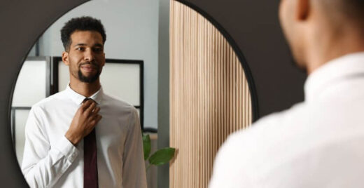 Man looking in the mirror and adjusting his tie