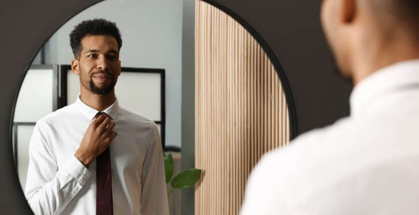 Man looking in the mirror and adjusting his tie